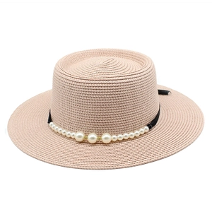 Dettaglio cappello di paglia beige con nastro nero e decorazioni di perle sintetiche