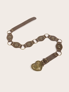 Detail of vintage heart buckle on brown PU leather belt with decorative metal studs