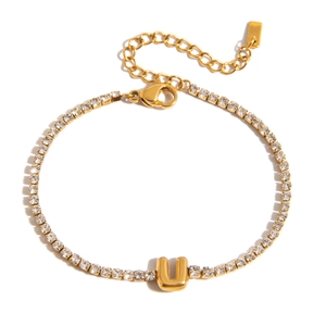 Macro detail of 18K gold-plated tennis bracelet with zircon-encrusted letter U pendant