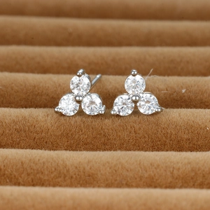 Macro shot of silver three-stone stud earrings set in brown velvet jewelry box