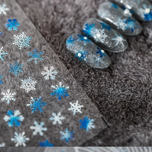 5D embossed snowflake nail stickers with blue and white winter ice patterns on gray glitter nails