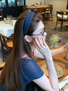Navy blue fabric headband for women with a textured finish on a model in a cafe setting