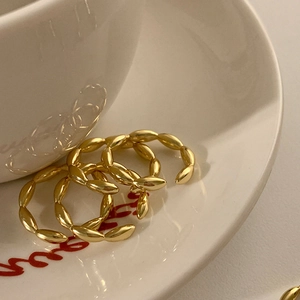Juego de tres anillos abiertos dorados con diseño de grano en plato de cerámica blanco