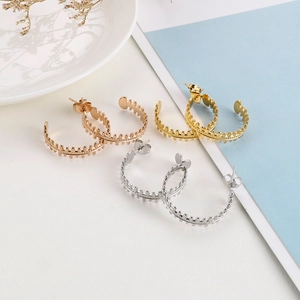 Macro shot of three pairs of C-shaped geometric hoop earrings in gold, rose gold and silver