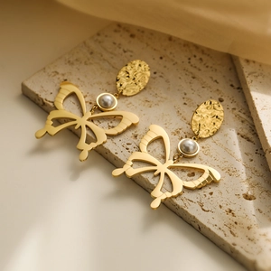 Gold plated titanium steel butterfly earrings with pearls on a natural stone surface
