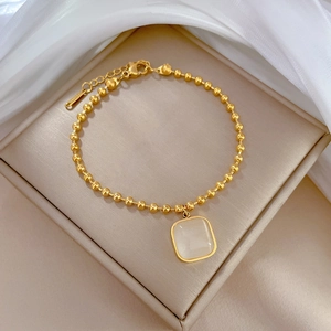 Nahaufnahme eines goldenen Titanstahl-Perlenarmbands mit quadratischem Katzenaugenstein