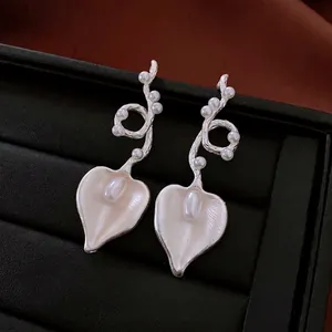 Vintage silver heart pearl drop earrings with elegant pearl accents on black leather