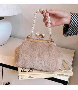 Detail of beige plush shell bag with gold ball clasp and elegant pearl handle straps