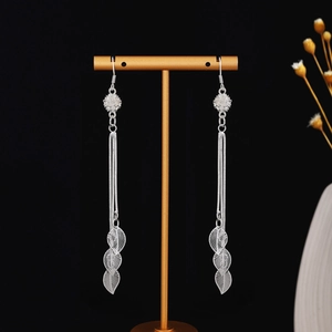Detail view of silver tassel earrings with delicate chains and hollow leaf pendants