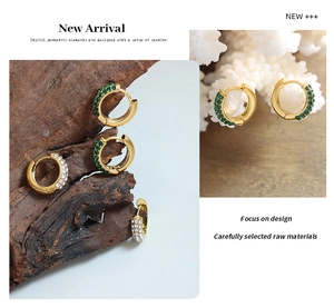 Detail of 18K gold plated hoop earrings with green and white zircon on wood and coral