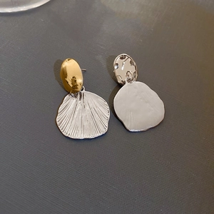 Vue détaillée du clou ovale doré et du pendentif argenté texturé sur les boucles bicolores
