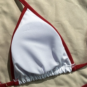Macro shot of red bikini top trim with white lining and precise stitching details