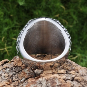 Macro view of wide silver stainless steel ring with brushed metal texture on a bark surface