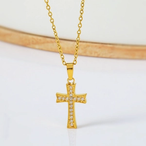 Golden micro-paved cross pendant necklace with sparkling zircons on a marble background