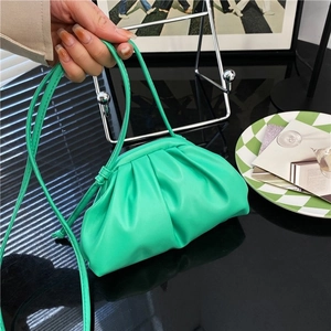 Bright green pleated cloud crossbody bag with thin strap shown in a lifestyle setting