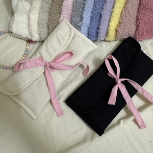 Détail de pochettes en tissu style ballet beige et noir avec des nœuds en ruban rose