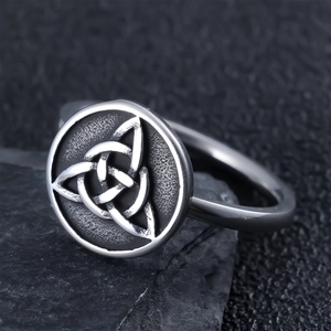 Macro shot of vintage Celtic Trinity Knot stainless steel ring on black rock