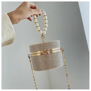 Close-up of a silver rhinestone cylinder evening bag with pearl handle and golden frame