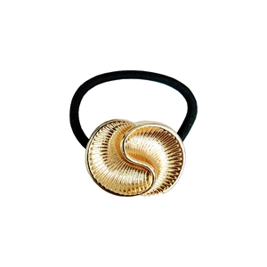 Detailed macro view of a minimalist golden shell-textured metal hair tie accessory