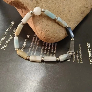 Detail showing natural amethyst and rectangular stone beads with silver spacers on a rock
