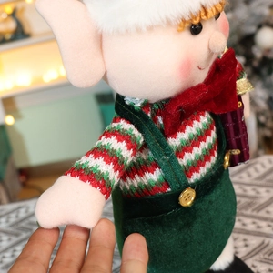 Close-up detail of a Christmas elf doll showing striped knit texture and velvet overalls