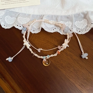 Detail eines gewebten Armbands mit bunten Natursteinen und weißen Seesternanhängern