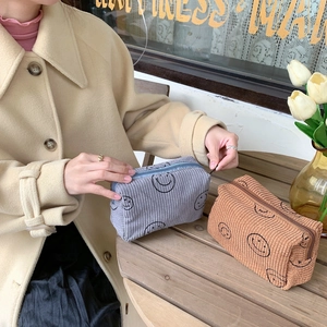 Detail of vintage corduroy makeup bag with smiling face pattern and zipper closure