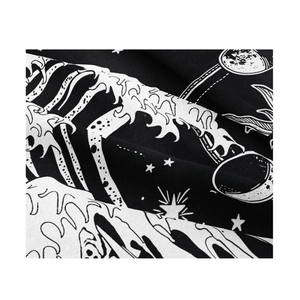 Detail shot of black tapestry with white moon, star, and wave patterns on textured fabric