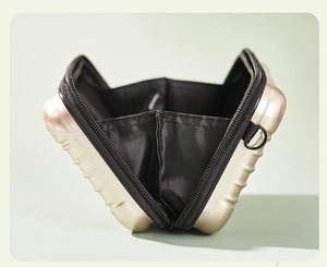 Detailed interior of a gold hard-shell mini makeup bag with black lining and metal D-ring