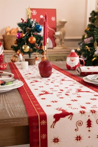 Detailed Christmas table runner with red reindeer and snowflake jacquard on a wooden table