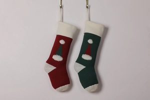 Detail view of red and green knitted Christmas stockings with 3D Santa hat motifs