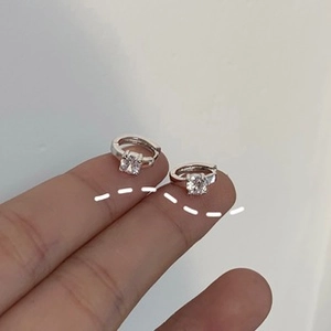 Makroansicht eines silbernen Creolen-Ohrrings mit einem quadratischen Zirkonia in Krallenfassung