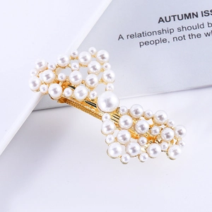 Macro detail of elegant golden alloy bow hair clip with white pearls and rhinestones