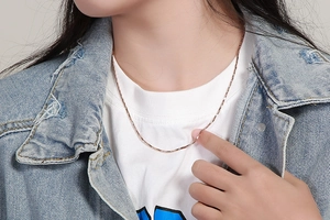 Close-up of a delicate rose gold snake chain necklace worn on a woman's neck