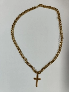 Detail of a gold stainless steel Cuban chain necklace featuring a classic cross pendant