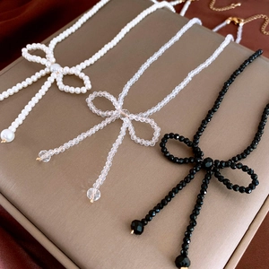 Elegant woven bow choker necklace featuring pearls and crystals on a velvet display