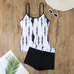 Flat lay of a two-piece tankini set with ink-stripe patterns and black swim shorts