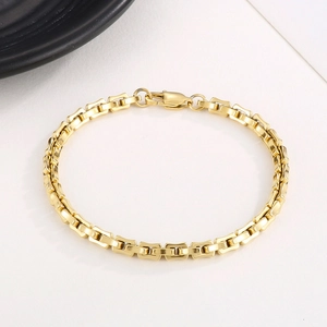 Detailed view of a gold-plated stainless steel rectangular link bracelet with lobster clasp