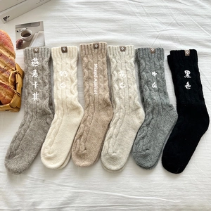 Detail view of six colors cable knit wool socks with leather labels on white bedding