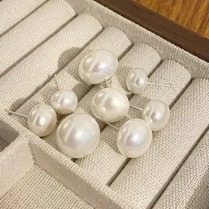 Macro view of assorted white pearl earrings with silver posts in a velvet jewelry box