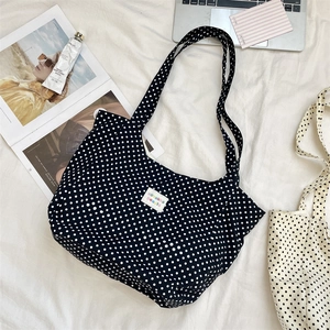 Overhead view of a large polka dot canvas tote bag with daily accessories and magazine