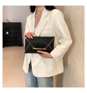 Dettaglio elegante borsa a mano intrecciata nera con chiusura dorata su una modella