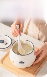 Close-up of hand using a ceramic spoon to scoop lard from a white porcelain storage jar