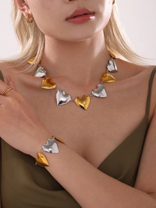 Detalle del conjunto de joyas con eslabones de corazón en oro y plata en una modelo
