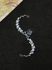 Detail of light blue floral beaded bracelet with silver butterfly and star charms