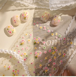 Detail view of floral nail stickers with gold hearts and butterfly knots on white pearls