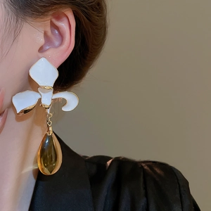 Detail of floral earrings with white petals, gold edges and amber water drop pendants