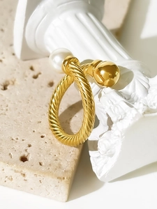 Close-up of twisted 18K gold titanium ring with a white pearl and a smooth metal bead
