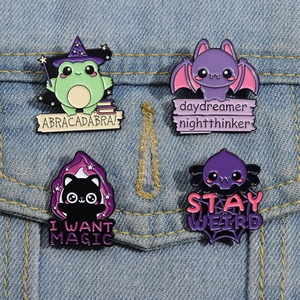 Set of four cute cartoon enamel pins featuring magic frog and bat on denim jacket