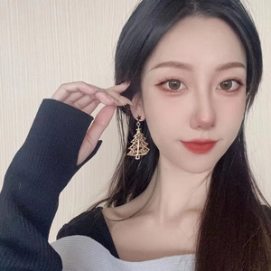 Detail of Christmas tree earrings with gold hollow design and black star studs on model